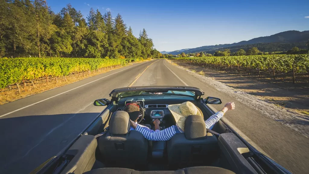 summer luxury destinations 2024 couple riding in convertible napa valley vineyards